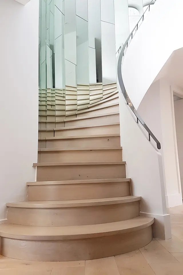 Curved staircase with glass detailing in a renovated property
